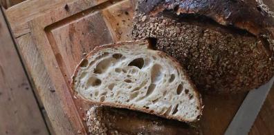 Slice of brown bread on wooden chopping board.